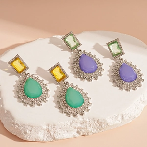 Vintage teardrop crystal earrings with colorful rhinestones on a white marble stone