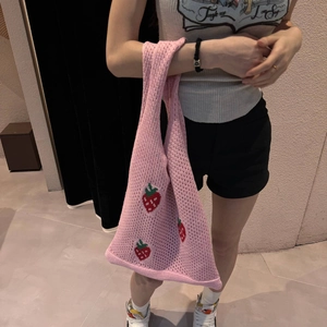 Detailed strawberry embroidery on pink knitted tote bag carried by model