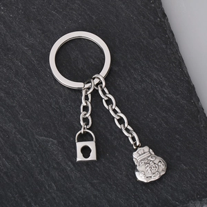 Close-up of stainless steel keychain with lucky money bag and lock charms on dark rock