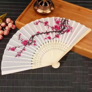 Detail of a white folding fan featuring delicate red plum blossom painting on bamboo ribs