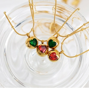 Gros plan de pendentifs boule dorés avec pierres de zircon en cœur vertes et rouges