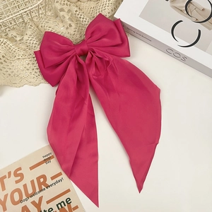 Rose red oversized satin bow hair clip with long ribbons on a stylish aesthetic background