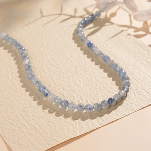 Close-up of blue stone beaded bracelet with natural textures on a warm beige background