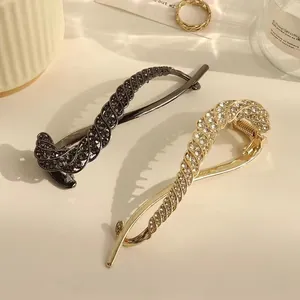 Detailed close-up of crystal-encrusted spiral hair clips in black and gold alloy