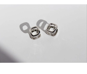 Artistic shot of silver square hollow earrings with elegant shadow on white backdrop
