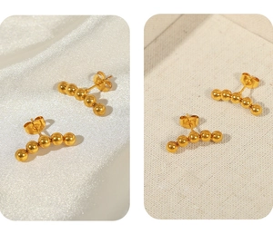 Detailed view of curved gold-plated stud earrings featuring five polished steel beads