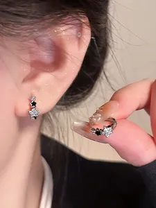 Vista macro de pendientes de estrella en plata con circonitas claras y esmalte negro