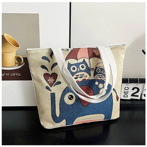 Detail of canvas tote bag featuring blue elephant and owls pattern on a desk