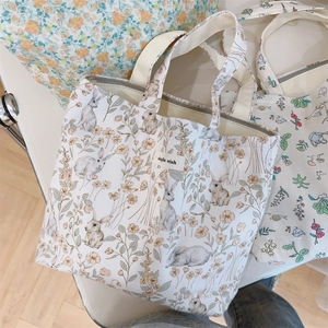 Close-up of cream canvas tote bag with rabbit floral print and zip closure detail