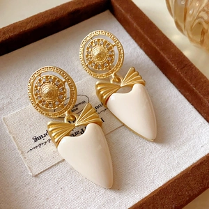 Vintage gold and white bow heart drop earrings displayed in a light fabric jewelry box