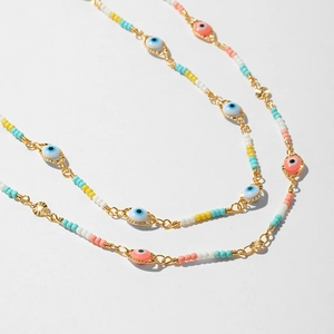 Detail of bohemian evil eye charm necklace with colorful seed beads and gold link chain