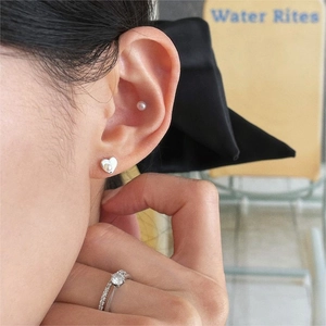 Close-up of 925 silver heart pearl earrings and sparkling cubic zirconia ring on a model