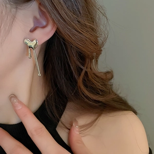 Detail of silver liquid lava heart earring on a model showing the fluid metal drop design