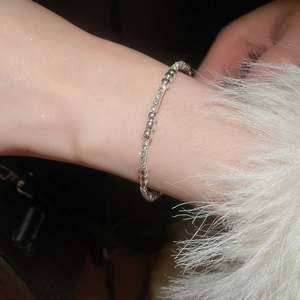 Détail du bracelet croisé argenté serti de zircons brillants sur poignet féminin