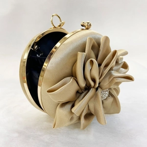 Macro detail of silk champagne gold round evening bag with 3D flower and crystal center