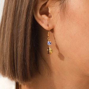 Chic gold tropical fish earrings with blue porcelain beads worn by a model