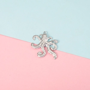 Macro shot of a silver metal octopus pendant with detailed tentacles on a pastel background