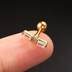 Macro shot of a golden stainless steel piercing stud with clear zircons on a fingertip