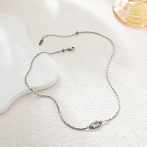 Macro shot of silver S925 necklace with square clear zircon pendant on white backdrop