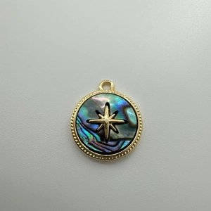 Detailed close-up of a round 18K gold-plated pendant with abalone shell and gold star