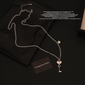 Detail of silver heart lock and key pendants on a delicate titanium steel chain