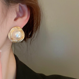 Detail of vintage large pearl earrings with gold twisted frame on a female model