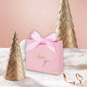 Sac cadeau rose Thank You avec ruban dans un décor festif de neige et sapins