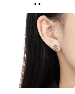 Detail of vintage S925 silver cross crown earring worn on a female model ear