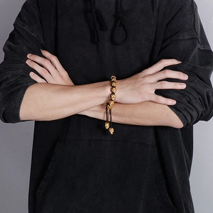 Detail view of gold skull beads on a black braided cord bracelet for men