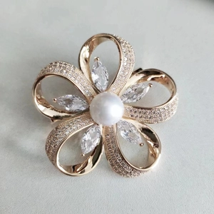Détail d'une broche fleur dorée avec perle blanche et oxydes de zirconium micro-pave