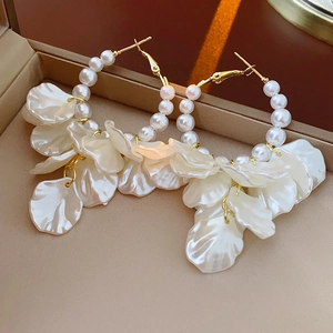 Gros plan de boucles d'oreilles pétales vintage avec perles sur écrin beige