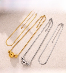 Detail of PVD plated gold and silver snake chains with triple bead pendant accents