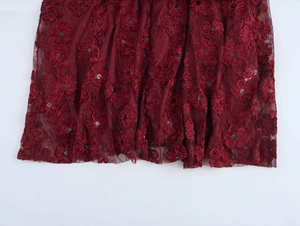 Detail of dark red lace dress featuring 3D floral embroidery and sparkling sequins