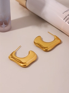 Detail of irregular C-shaped pleated gold earrings with 18K PVD plating texture