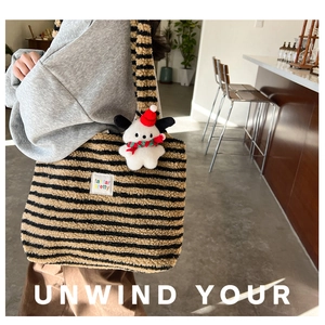 Close-up of brown striped plush tote bag featuring a cute puppy doll pendant accessory