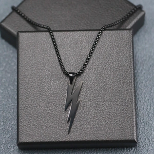 Polished black stainless steel lightning bolt pendant necklace on a textured gift box