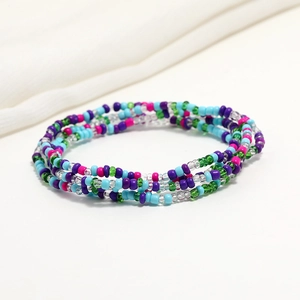 Detailed close-up of bohemian double-layered colorful glass seed bead waist chain on white fabric