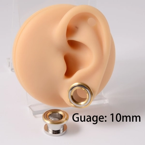 Macro shot of 10mm gold and silver ear gauge expander on a silicone ear model
