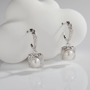 Detailed shot of s925 silver pearl drop earrings with hand-hammered texture frame