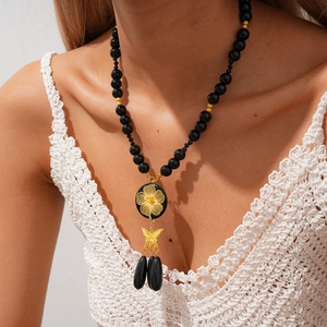 Detailed macro of vintage black beaded necklace with floral medal and butterfly pendant