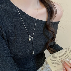 Detail of silver Y-shaped pearl necklace with baroque pendant on a female model