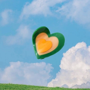Sweet heart-shaped green and orange acetate hair claw clip set against a clear blue sky