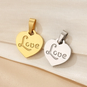 Macro shot of 18K gold and silver heart pendants with Love engraving on soft fabric