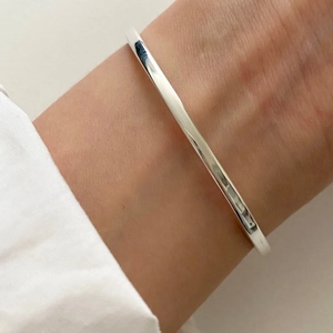 Close-up of a 3mm minimalist S925 sterling silver square wire bangle worn on the wrist