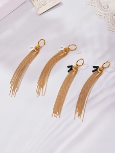 Detailed view of gold tassel earrings with black and white accents on silk fabric