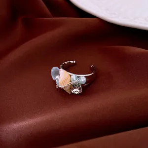 Bohemian ocean shell ring with blue beads and zircon on brown silk background