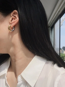 Close-up of chunky gold and silver bicolor spliced hoop earrings on model ear