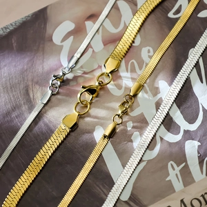 Flat lay of gold and silver stainless steel snake bone necklaces in varied widths
