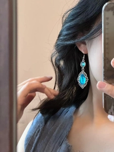 Detailed close-up of vintage blue resin oval earrings with ornate silver lace borders