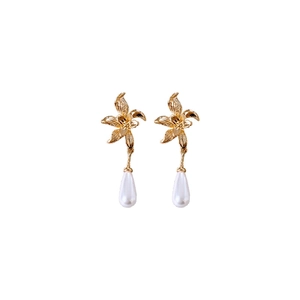 Elegant gold plated flower earrings with white teardrop pearl drops on white background